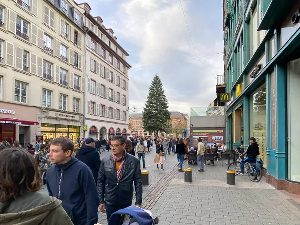 Пешеходы, идущие по главной улице Страсбурга с высокой елкой на заднем плане во время ежегодного Рождественского рынка — стоковое фото