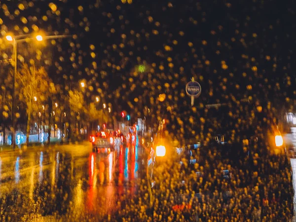 Defocused rainy street seen through the car windshield with cars and buses driving fast — ストック写真