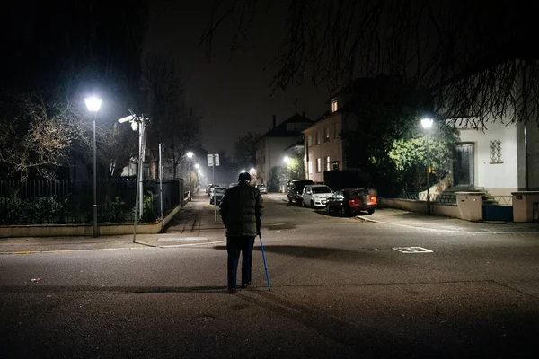 Camminare da solo silhouette di uomo anziano che cammina sulla strada francese di notte utilizzando bastone preservando l'equilibrio con canna di alluminio telescopica blu Assistenza medica e riabilitazione — Foto Stock