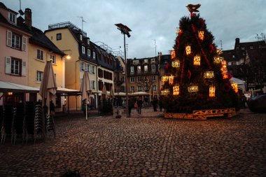 Yerel halk ve turistler küçük süslü Noel ağacını geziyorlar.