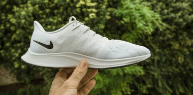 Pov erkeği, Nike modeli Zoom Rival Fly tarafından üretilen, siyah logolu kadınlar için üretilen yeşil arka plan profesyonel koşu ayakkabısına karşı el ele tutuşuyor.