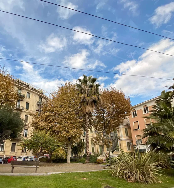 Pequeno parque no centro de Sanremo Itália com céu azul com algumas nuvens dispersas e palmeira alta — Fotografia de Stock