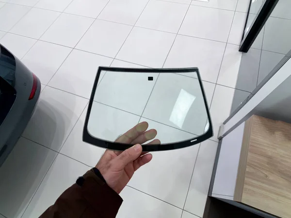 車の自動車修理店センター内にミニチュアガラスのフロントガラスを保持している人の手のpov — ストック写真