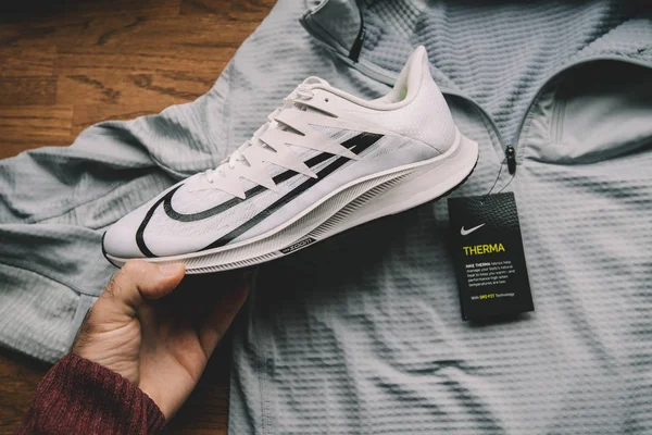 Pov muž ruka drží Nike Zoom Rival Fly profesionální běžecké boty pro ženy s Nike Derma Dry-Fit oblečení v pozadí — Stock fotografie