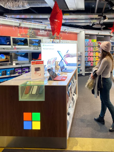 Mujer admirando múltiples tabletas Microsoft Surface y portátiles para la venta en el stand dedicado de Microsoft dentro de FNAC tienda electrónica francesa centro comercial antes del Viernes Negro — Foto de Stock