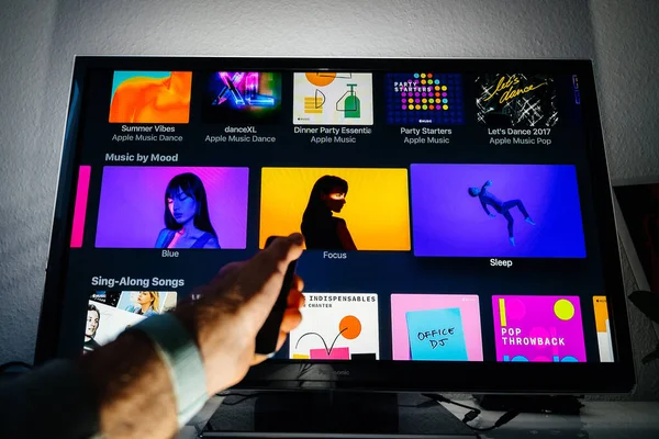 Mão de homem segurando controle remoto do aplicativo Apple TV Music — Fotografia de Stock