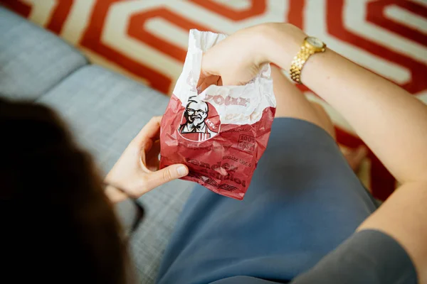 Woman taking from the KFC meat paper bag fresh delicious meat - overhead view in living room couch — Stock Photo, Image