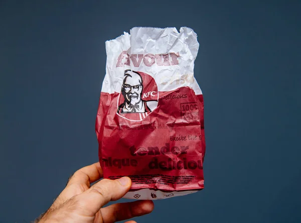 Man hand håller Kfc kött papperspåse med färska läckra kött isolerad på blå grå bakgrund — Stockfoto