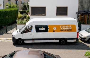 Sixt 'den Volkswagen minibüsün hava görüntüsü kiralık bir araba şirketi ve kabinin içindeki akıllı telefondan konuşan bir erkek sürücü.