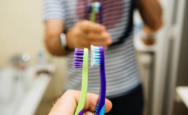 Man hand holding old and new toothbrush in hand in front — Stock Photo, Image