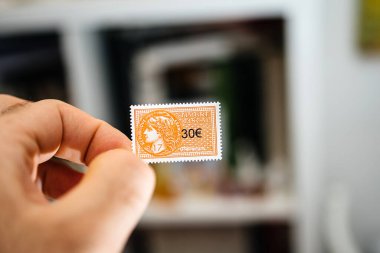 Paris, France - Mar 17, 2019: Man hand holding 30 euro fiscal revenue stamp timbre fiscale used for French administration