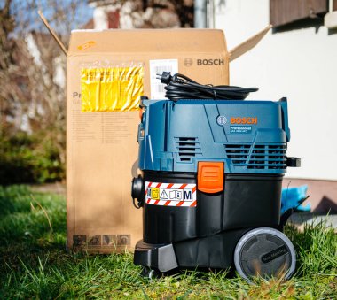Strasbourg, France - Feb 9, 2020: New professional Bosch GAS 35 M AFC Wet Dry Vacuum Cleaner on green grass near reconstructed home - M filter class