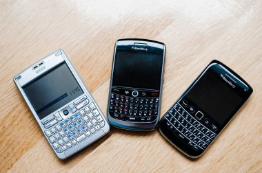London, United Kingdom - Apr 21, 2013: Unique overhead view of three modern smartphones telephones manufactured by Nokia and Blackberry with full qwerty keyboard