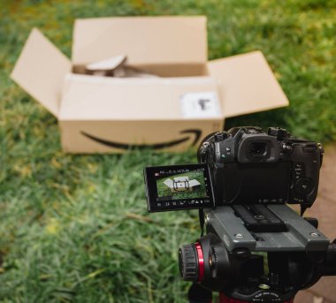 Paris, Fransa - 23 Şubat 2020: Amazon Prime 'dan Panasonic Gh5 aynasız kamera ve çimenlerde logoti olan mukavva kutulu bir perakendecinin boks işlemleri için kurulumu