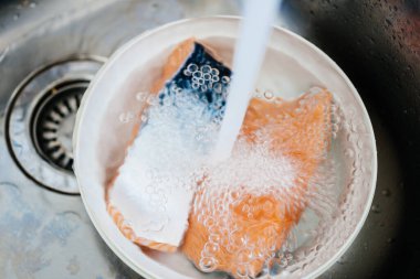 Mutfakta yıkanan su paslanmaz çelik lavabo ve iki parça plastik kase içeriyor.