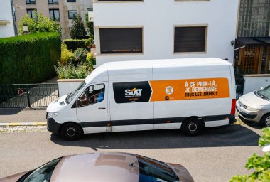 Sixt 'den Volkswagen' in minibüsünün genel manzarası. Bir araba kiralama servisi ve kabinin içindeki akıllı telefondan konuşan bir erkek sürücü.