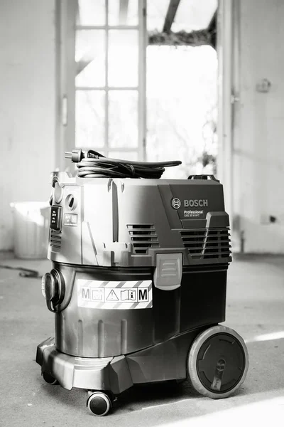 Blanco y negro Vista frontal de Bosch Professional Gas 35 M Clase AFC con sistema automático de limpieza del filtro extractor en el suelo de hormigón de obra —  Fotos de Stock