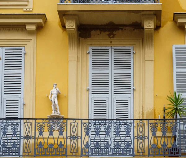 Вид з вулиці великого балкона, пофарбованого в жовтий з антикварною статуєю — стокове фото