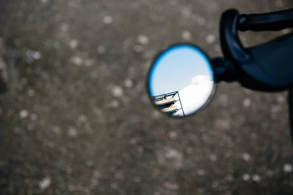 View of part modern building reflected in motorcycle round rear view — Stok fotoğraf