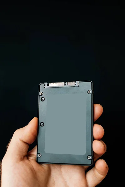 Człowiek trzyma rękę na czarnym tle nowy potężny dysk SSD Solid State Drive — Zdjęcie stockowe