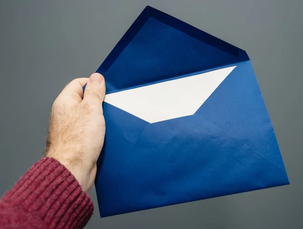 Man hand met blauwe envelop tegen grijs — Stockfoto