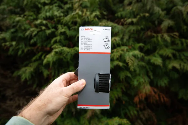 Man hand hålla mot grön trädgård bakgrund Bosch 35mm rund borste för professionell dammsugare våta rengöringsmedel — Stockfoto