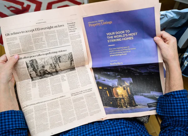 Pov of senior hands holding latest Financial Times newspaper reading the Property Listing advertising supported by Sothebys and other economic and financial articles — Zdjęcie stockowe