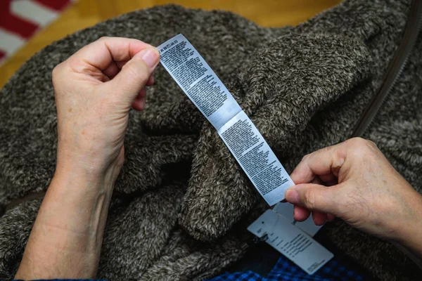 Pov των ηλικιωμένων χεριών κρατώντας εθιμοτυπία ρούχα ενός ζεστού παλτό Uniqlo — Φωτογραφία Αρχείου