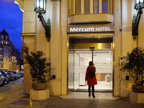 Fasade av Accor Mercure Hotel i sentrum med ensomme kvinner som går inn automatiske dører i skumringen – stockfoto