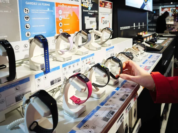 Mujer eligiendo a mano el nuevo dispositivo portátil Fitbit smartwatch en la tienda de electrónica FNAC en el centro de Niza —  Fotos de Stock
