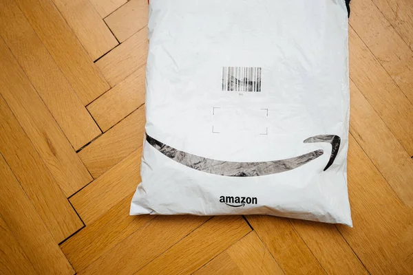 Бросается на паркетный пол свежая полученная посылка от Amazon Prime с логотипом стрелки улыбки — стоковое фото