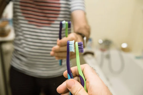 POV uros käsi tilalla vanha ja uusi hammasharja kädessä edessä kylpyhuone — kuvapankkivalokuva