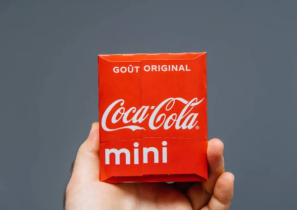 Mano de hombre sosteniendo sobre fondo gris paquete de bebida dulce Coca-Cola - Edición francesa con inscripción de bebida original —  Fotos de Stock