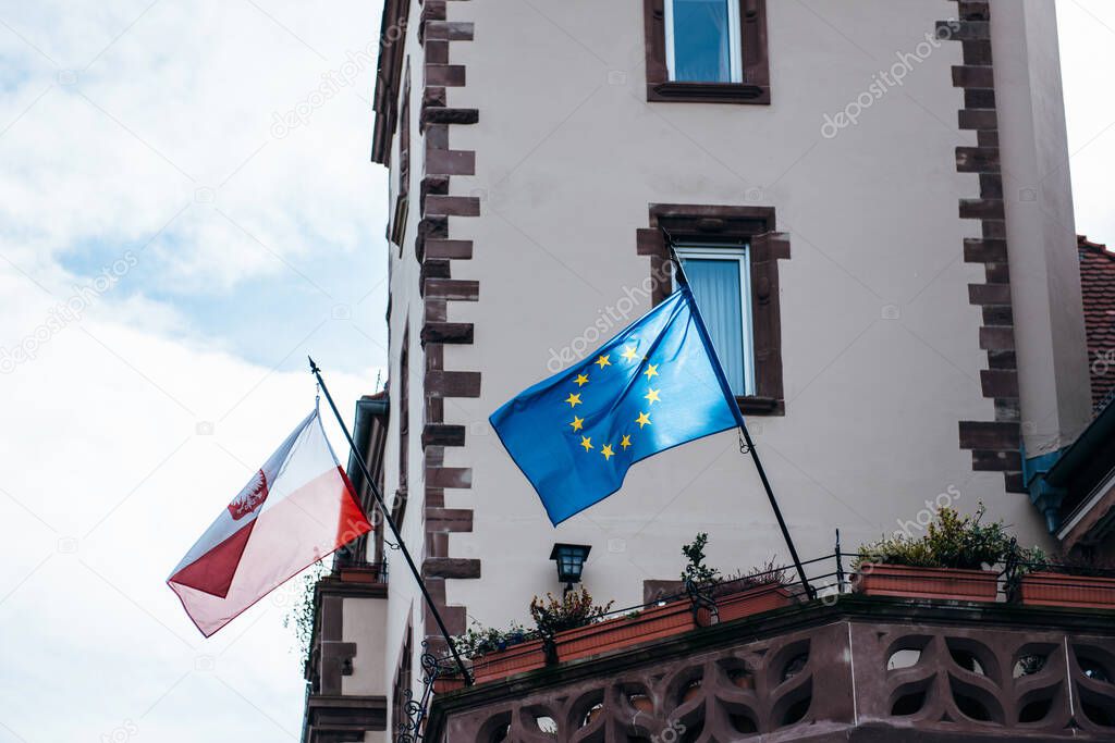 Waving Flag with the coat of arms of Poland and European Union flags waving above the entrance