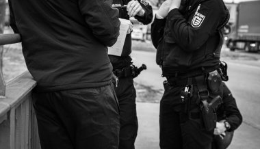 Tanınmayan Alman polisinin siyah beyaz görüntüsü. Polis, sınırdaki insanları kontrol ediyor.