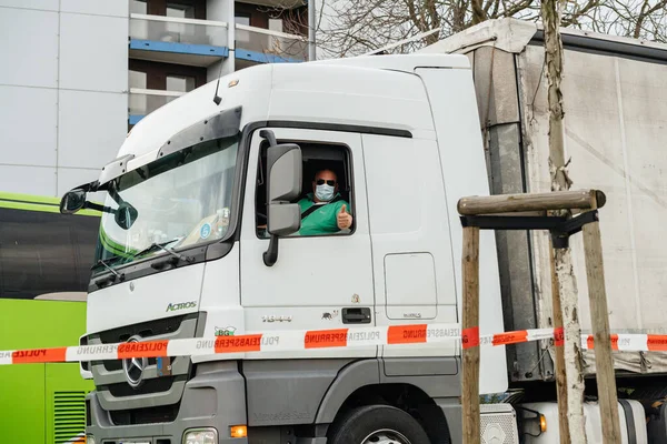 Kierowca ciężarówki w Mercedes-Benz Actros w masce ochronnej pokazuje Ok znak — Zdjęcie stockowe