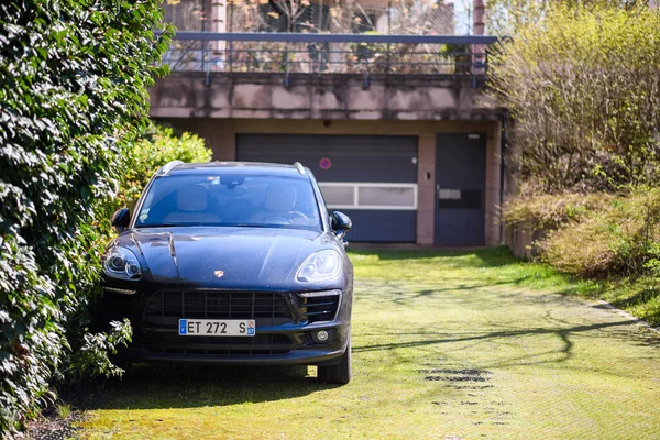 Beautiful new Porsche Cayenne SUV parked in front of large garage door — Stock Photo, Image