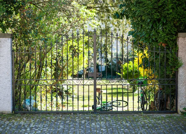 Puerta de acero forjado entrada al jardín de lujo con múltiples bicicletas estacionadas detrás — Foto de Stock