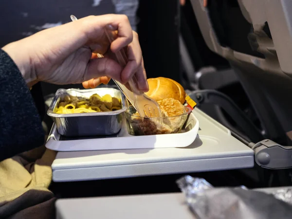 Mulher segurando garfo e faca comendo deliciosa refeição na economia moderna de aeronaves — Fotografia de Stock