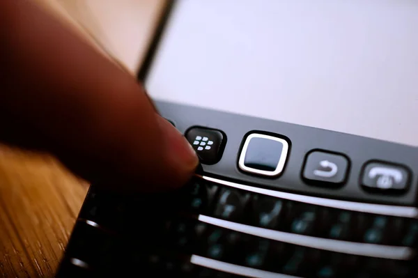 Main de l'homme appuyant sur le bouton Blackberry RIM smartphone home — Photo