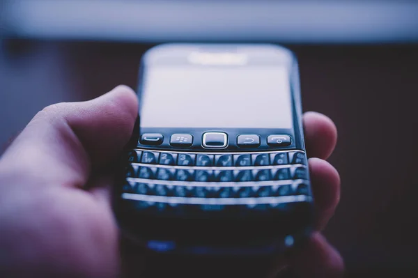 Mano masculina sosteniendo el viejo teléfono inteligente Blackberry vintage — Foto de Stock