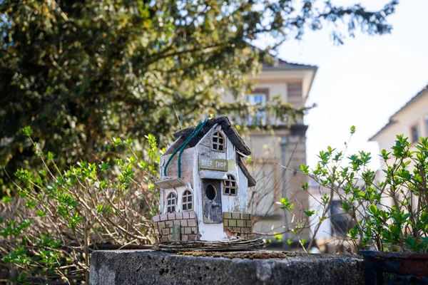 Pequeña casa de pájaros en una valla de piedra con una inscripción divertida — Foto de Stock