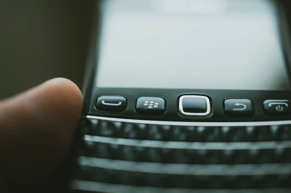 Αρσενικό χέρι κρατώντας Blackberry smartphone τηλέφωνο με έμφαση στην εικονική μάρκα — Φωτογραφία Αρχείου