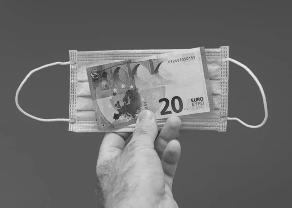 Homem mão segurando pilha de dinheiro com máscara respiratória — Fotografia de Stock