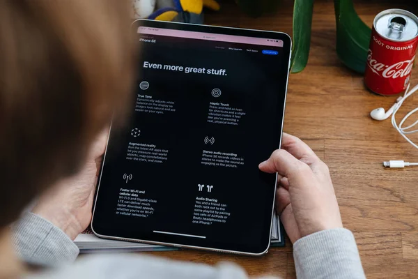Жінка дивиться на новий iPhone Se на планшеті iPad Pro — стокове фото