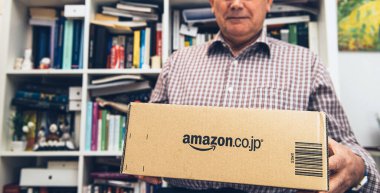 Oturma odasında tutulan kıdemli adam Amazon Prime 'dan yeni teslim edilmiş bir paket getirdi.