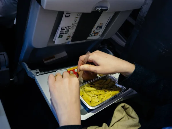 Женщина, питающаяся вкусной едой в современном авиационном экономическом бизнес-классе — стоковое фото
