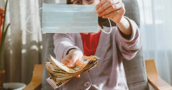 Женщина предлагает за пачку денег банкноты хирургическая процедура медицинская маска для лица — стоковое фото