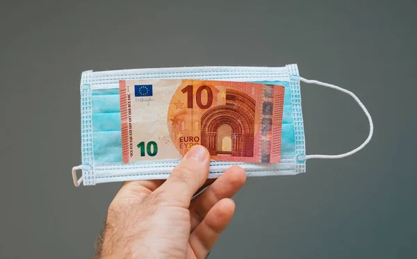 Homme main tenant pile d'argent avec masque respiratoire — Photo