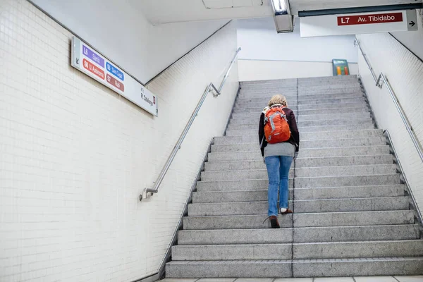 Ззаду видно одиноку жінку, що піднімається сходами на станції метро Барселони. — стокове фото